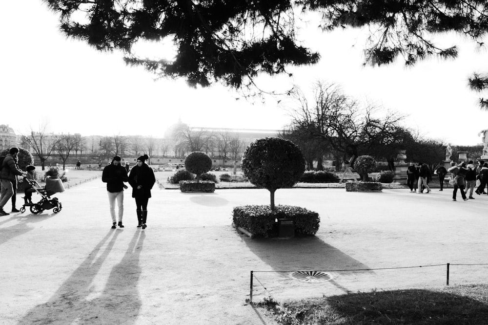 a black and white photo of people walking in a park