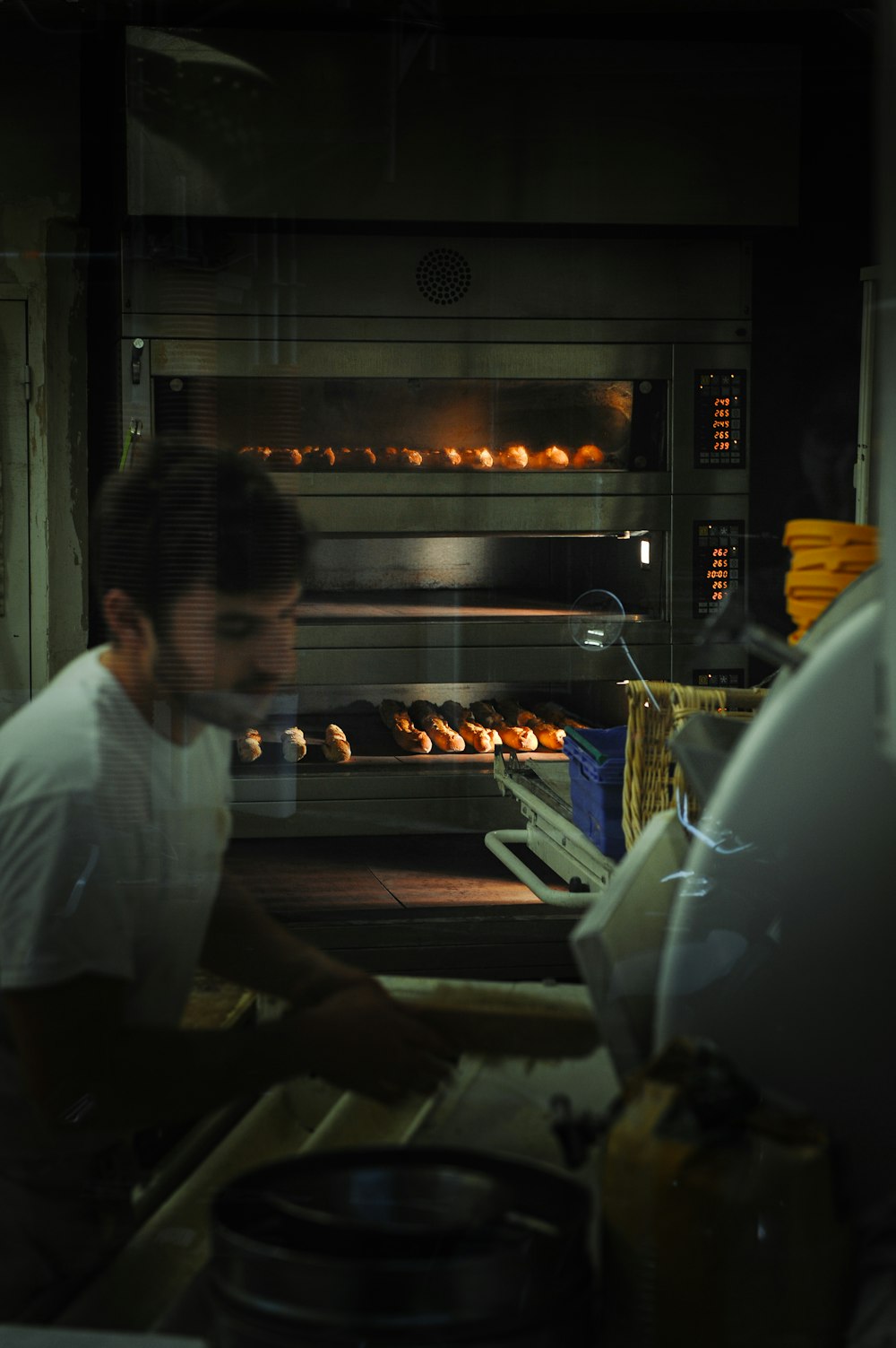 a man in a white shirt is putting donuts into an oven