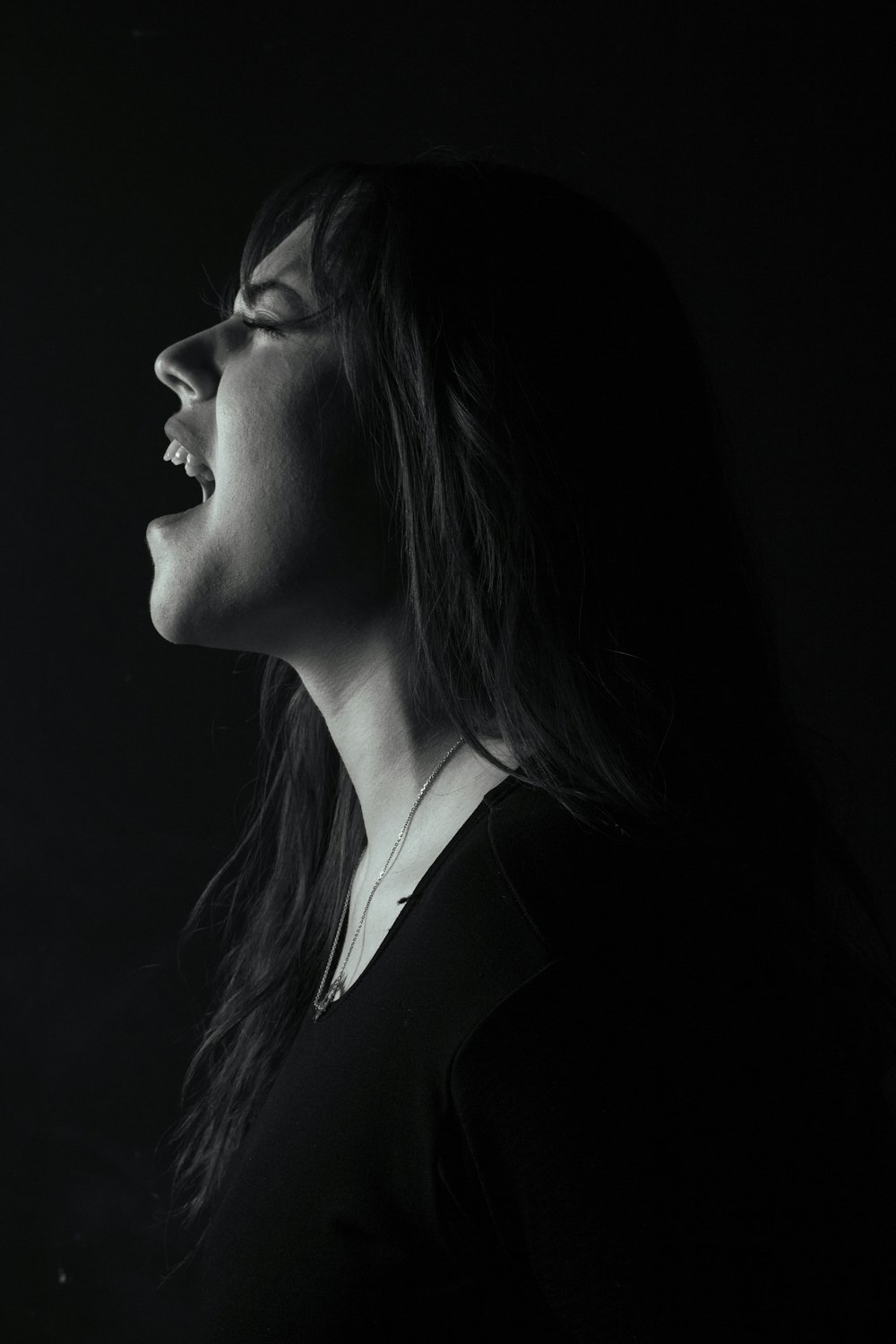 a woman singing into a microphone in the dark