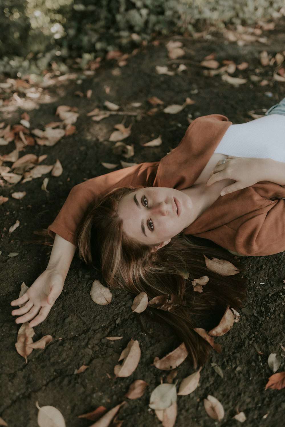 a woman laying on the ground in the leaves