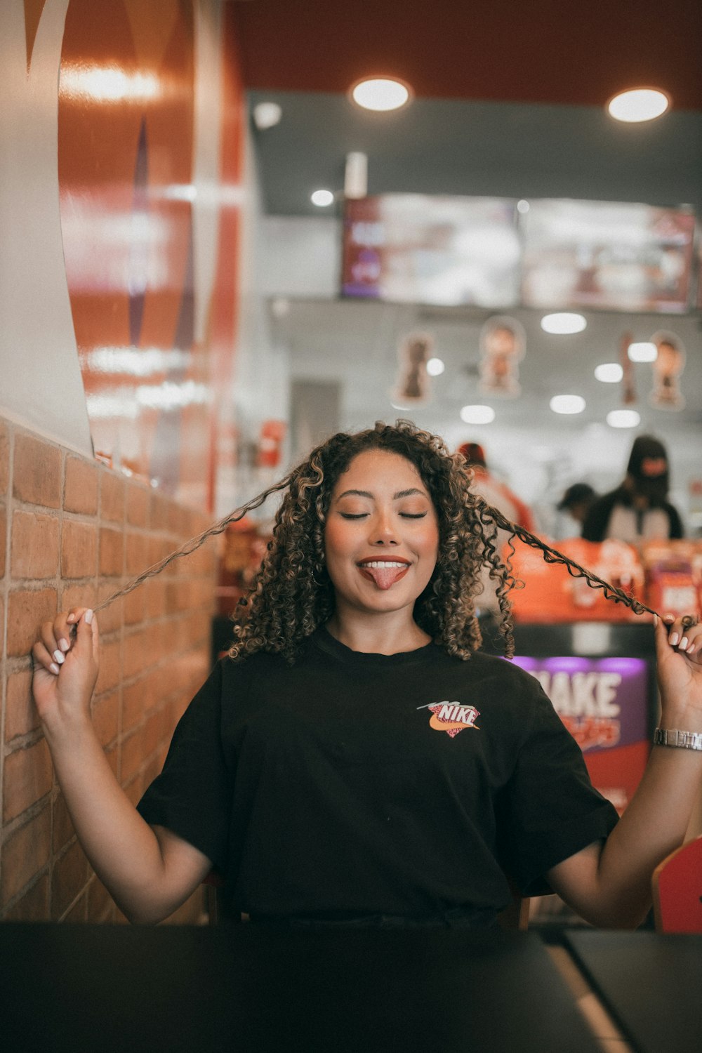 a woman with curly hair standing in front of a brick wall