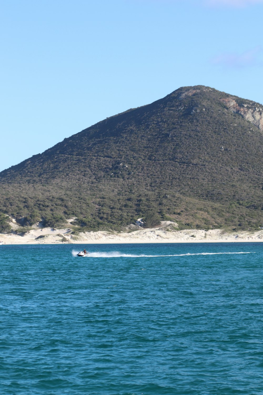 a boat in the water with a mountain in the background