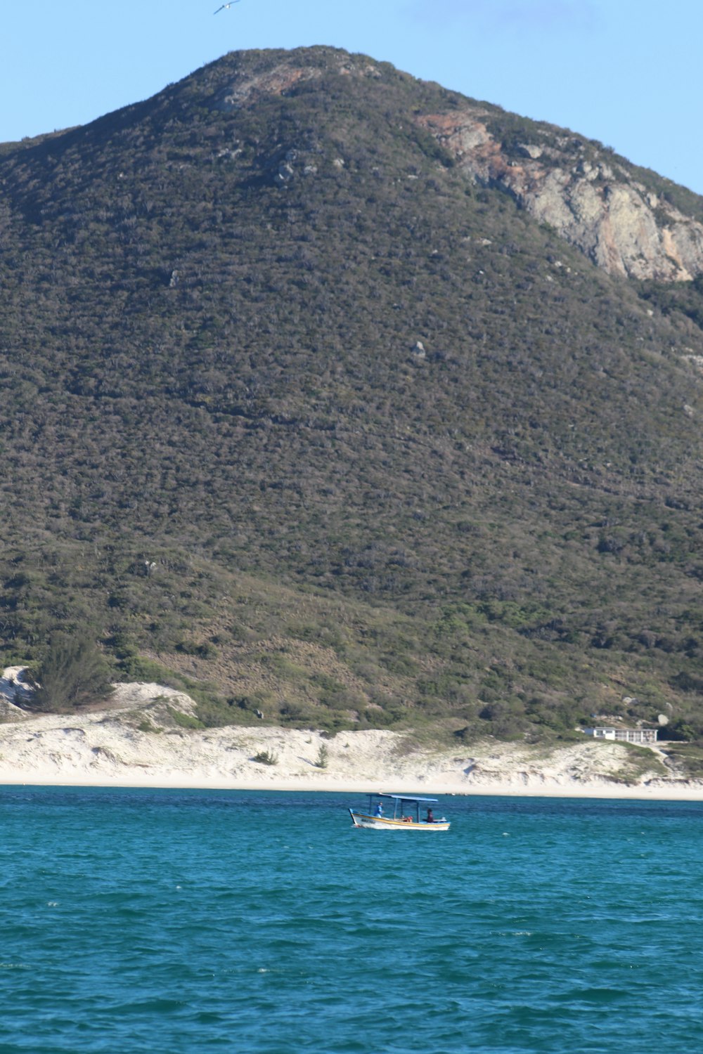 a boat in a body of water with a mountain in the background