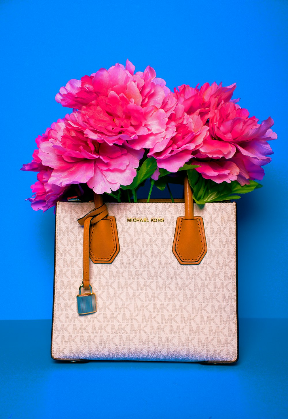 a white michael korsh bag with pink flowers in it