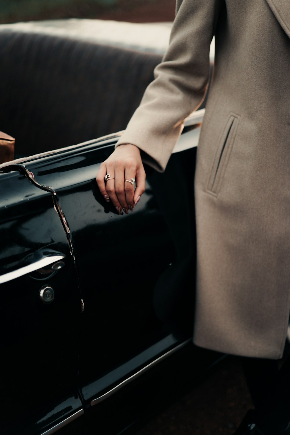 a person in a coat is holding onto a black car