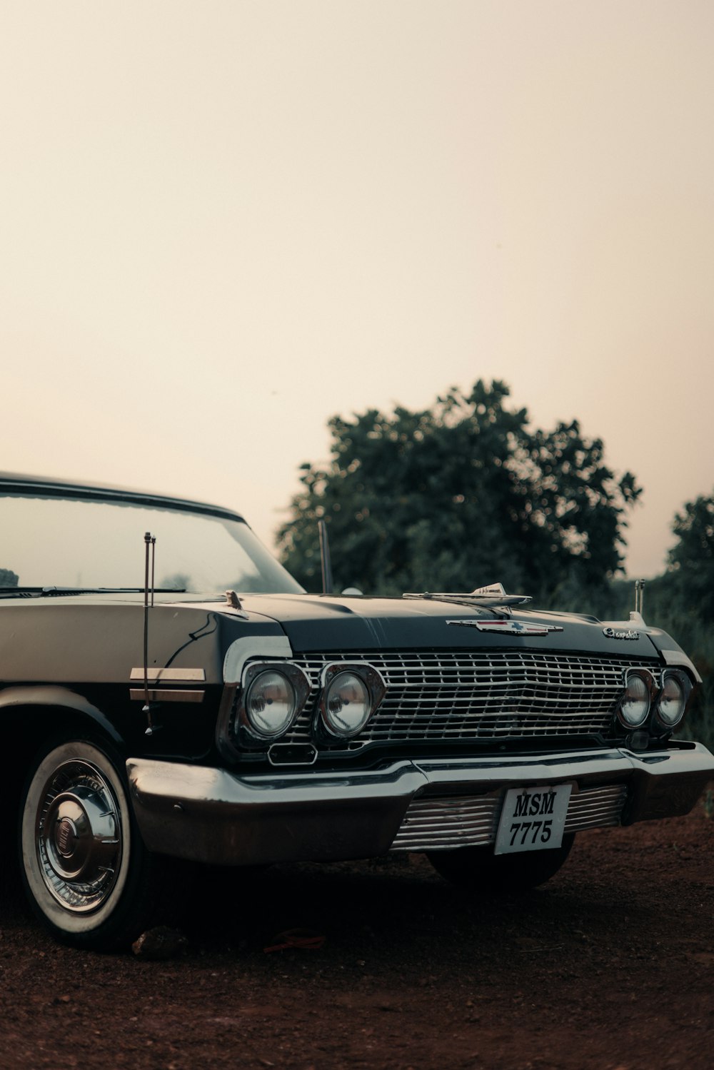 a black and white car parked on a dirt road