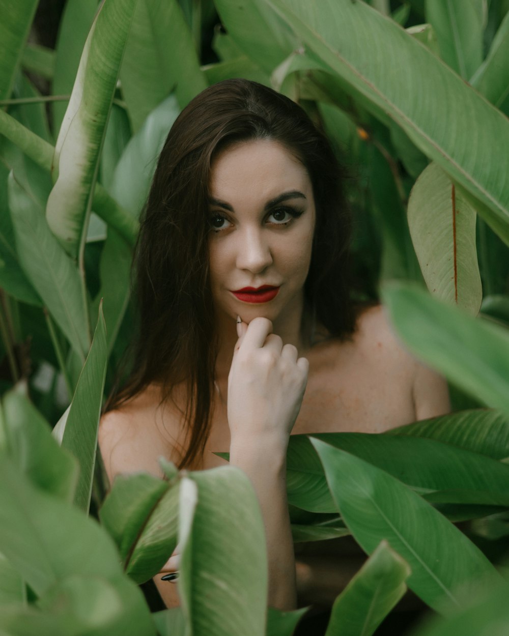 a woman with red lipstick standing in a field of leaves