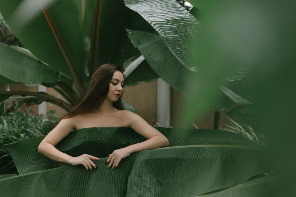 a woman in a green dress sitting on a plant