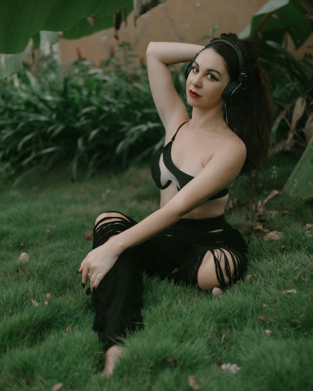 a woman sitting in the grass wearing headphones