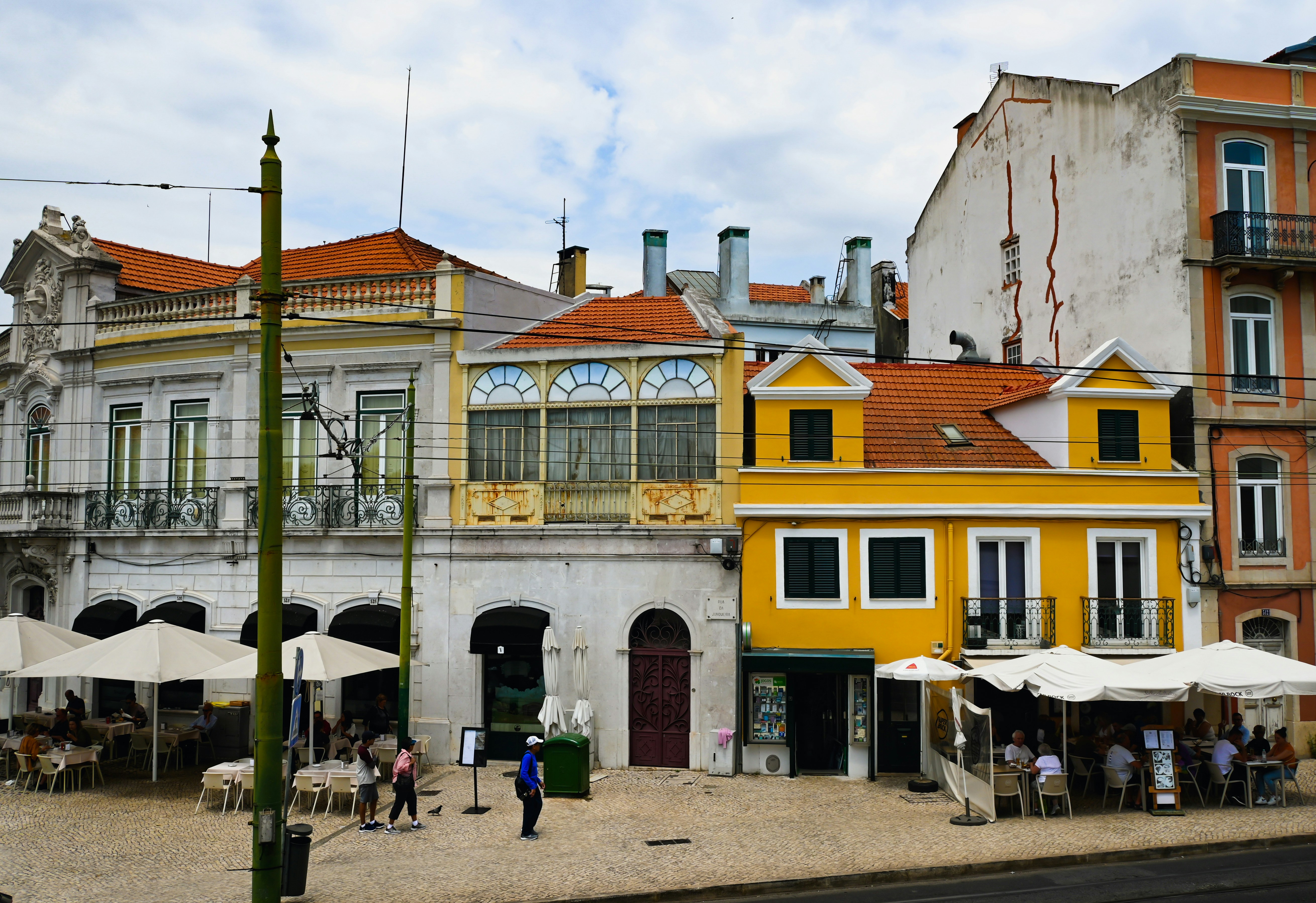 a group of people standing outside of a yellow and white building