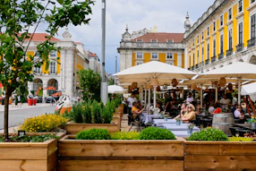 a group of people sitting at tables under umbrellas
