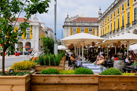 a group of people sitting at tables under umbrellas