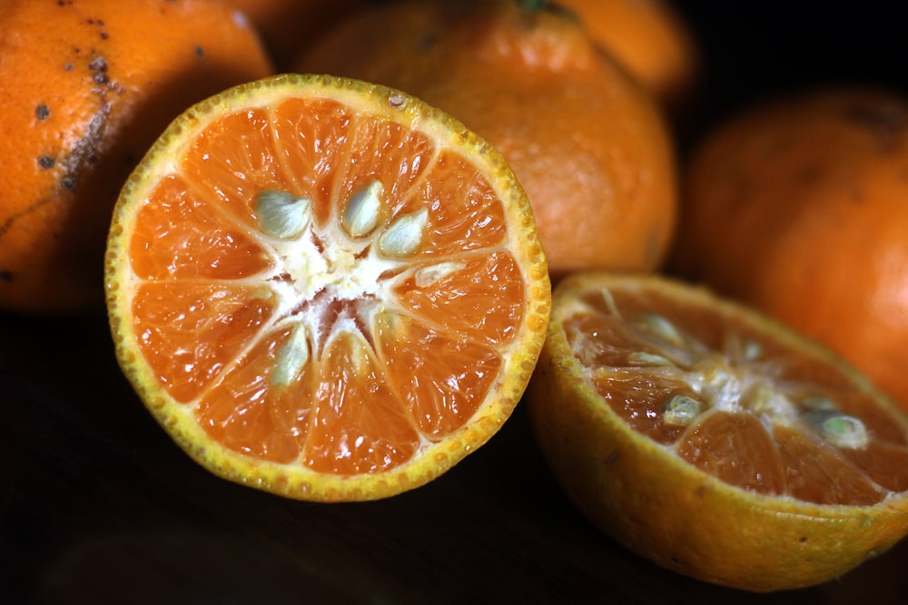 an orange cut in half sitting next to other oranges