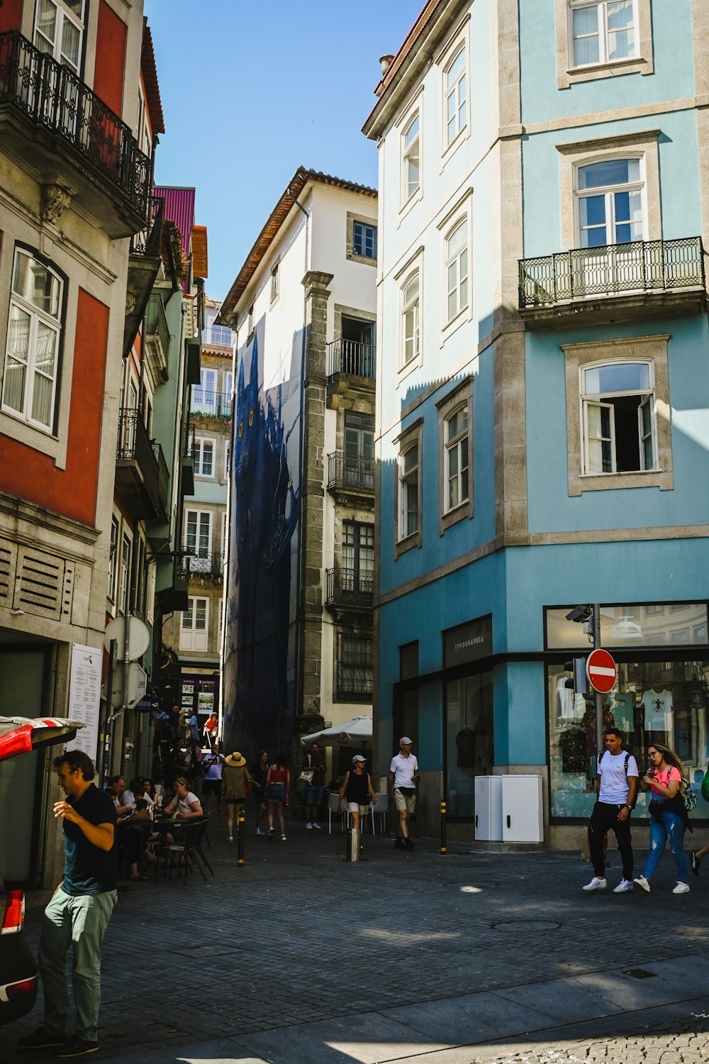 a group of people walking down a street next to tall buildings