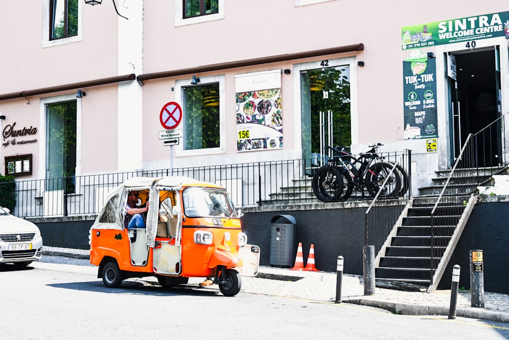 an orange and white tuk tuk parked in front of a building
