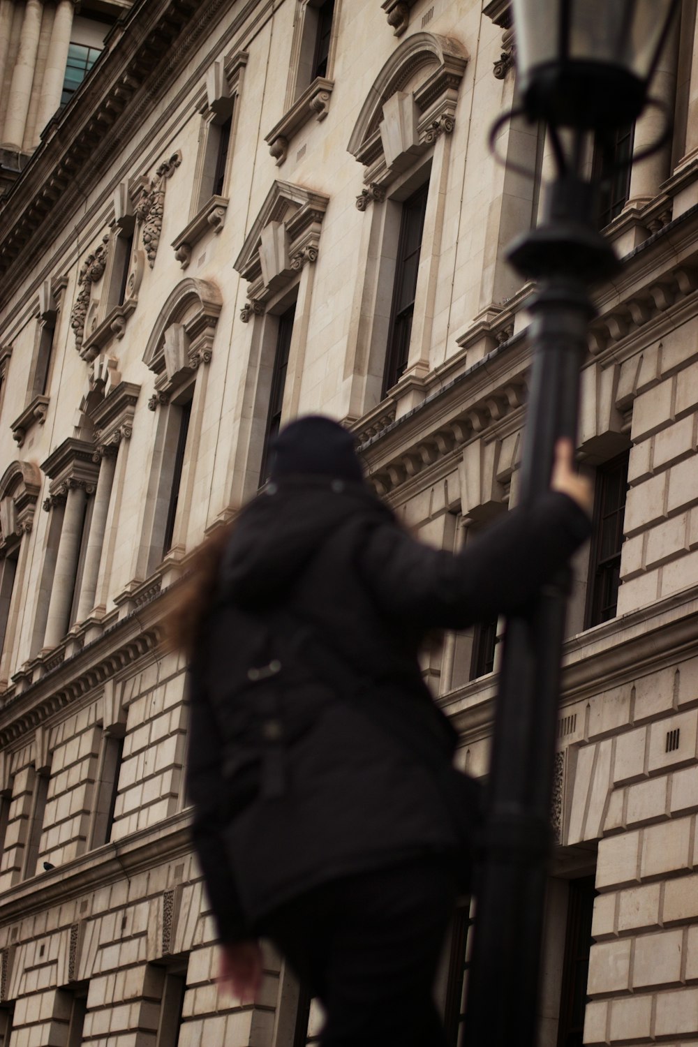 a woman walking down a street next to a tall building