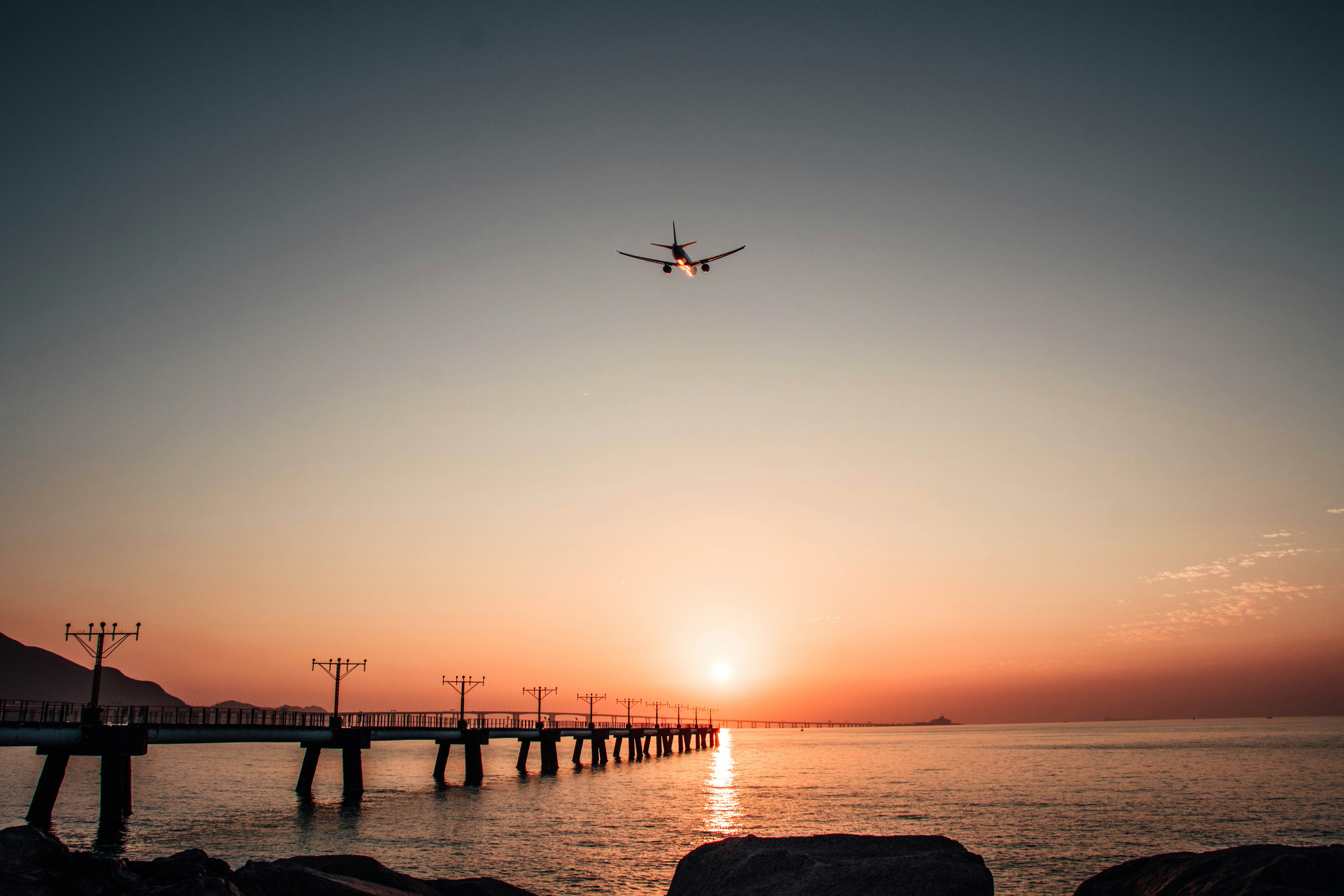 a plane flying over a body of water at sunset, 