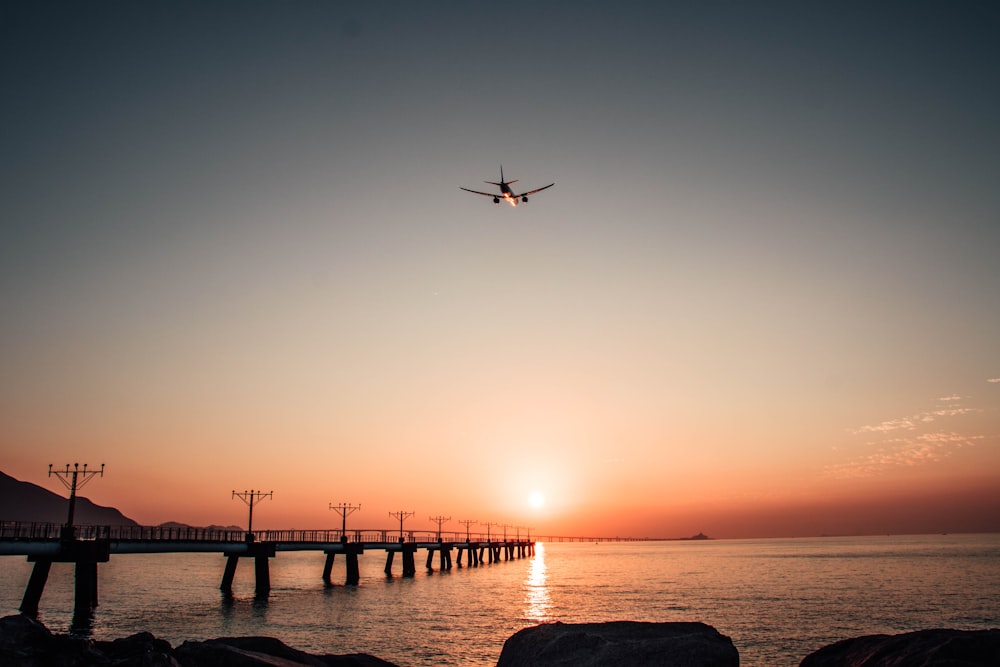 a plane flying over a body of water at sunset