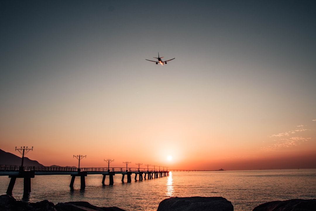 a plane flying over a body of water at sunset,