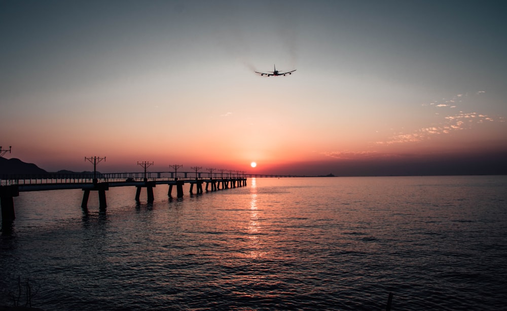 a plane flying over a body of water at sunset