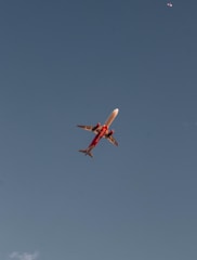 a red and white airplane flying in a blue sky