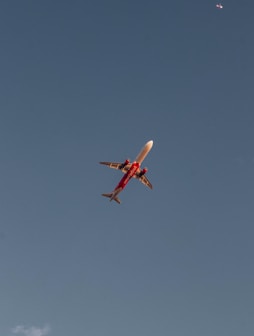 a red and white airplane flying in a blue sky