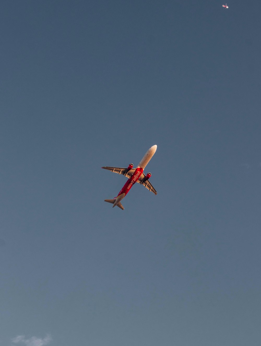 a red and white airplane flying in a blue sky