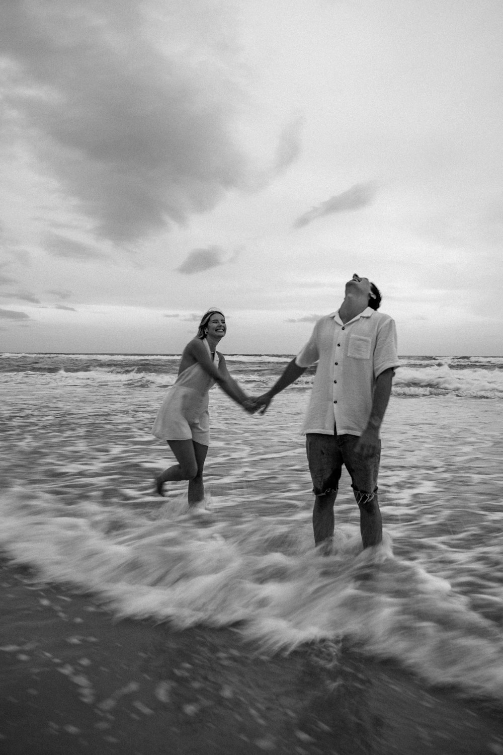 a man and a woman holding hands while standing in the ocean