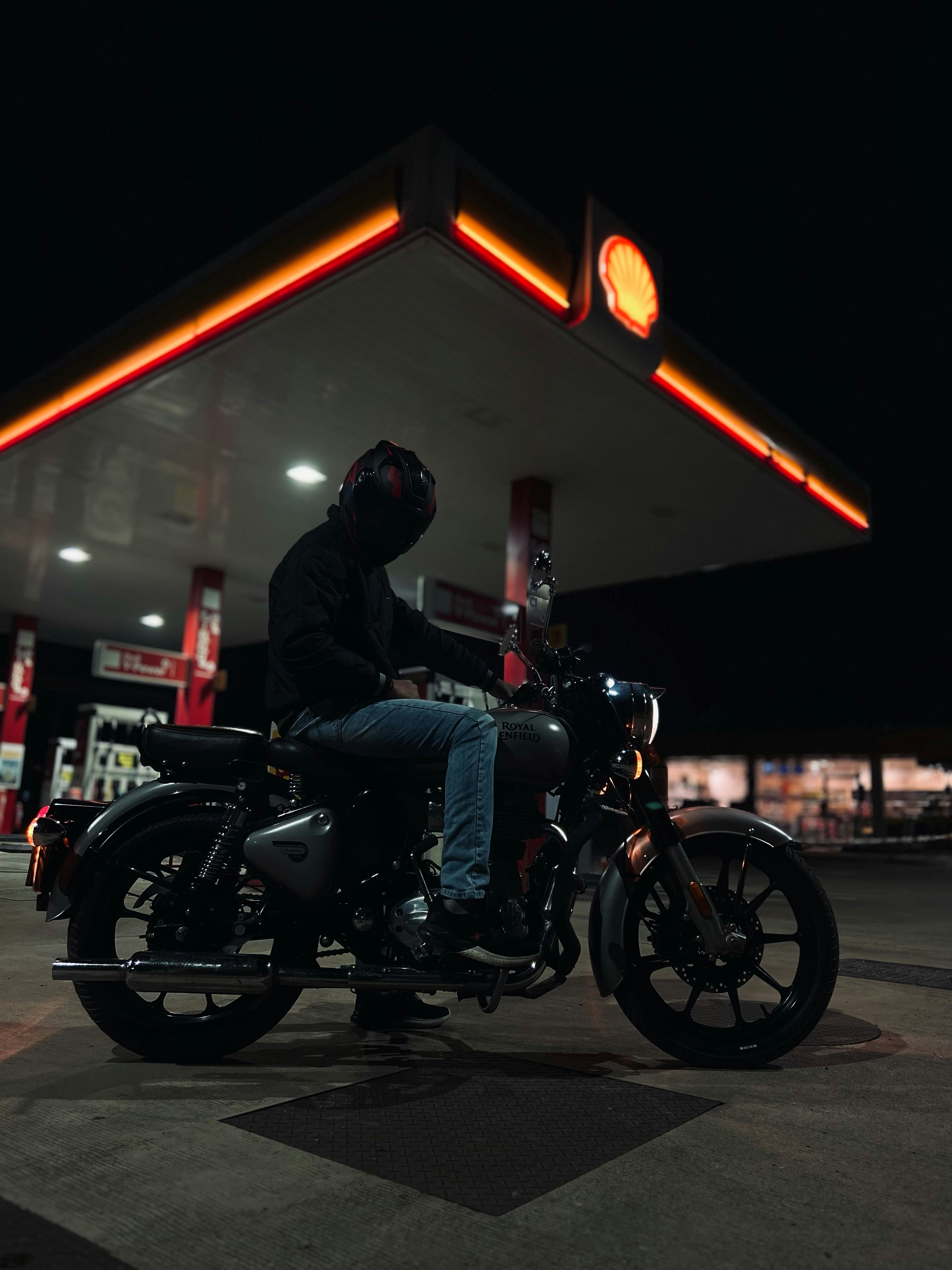 a man sitting on a motorcycle at a gas station