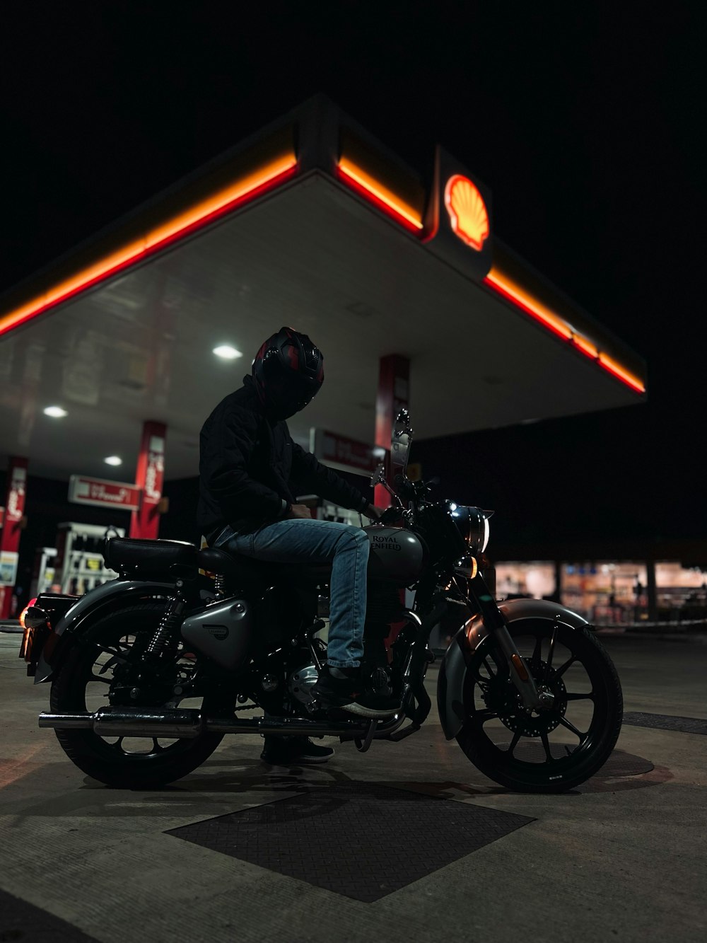 a man sitting on a motorcycle at a gas station