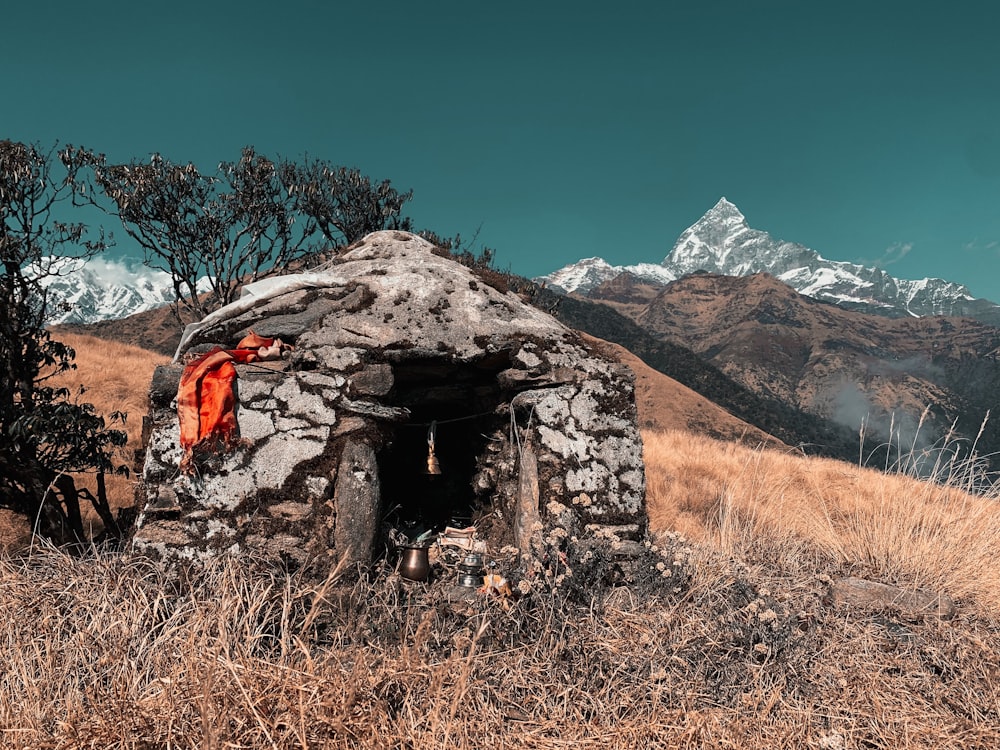 an old stone hut in a field with mountains in the background
