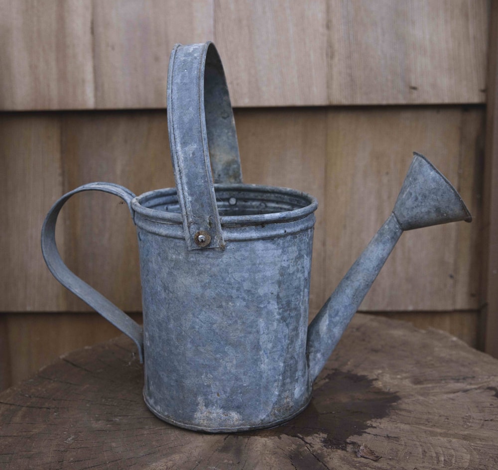 a metal watering can with a shovel sticking out of it