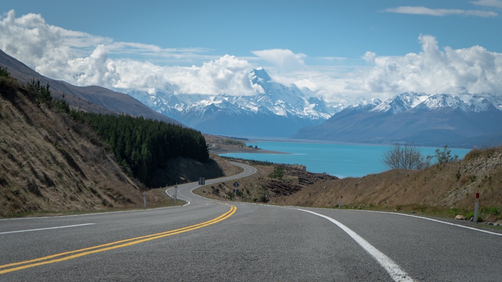 a road with mountains in the background and a body of water in the foreground