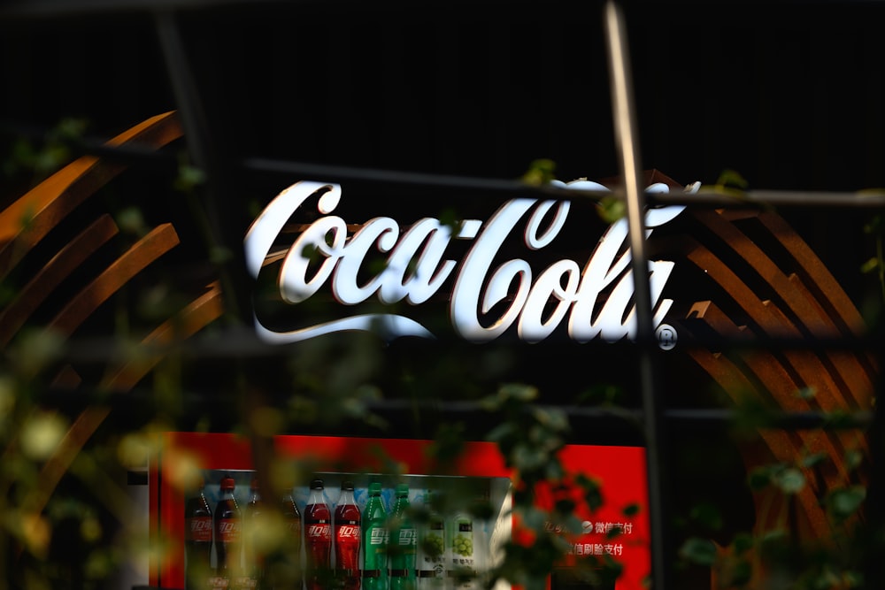a coca - cola sign is seen through a window