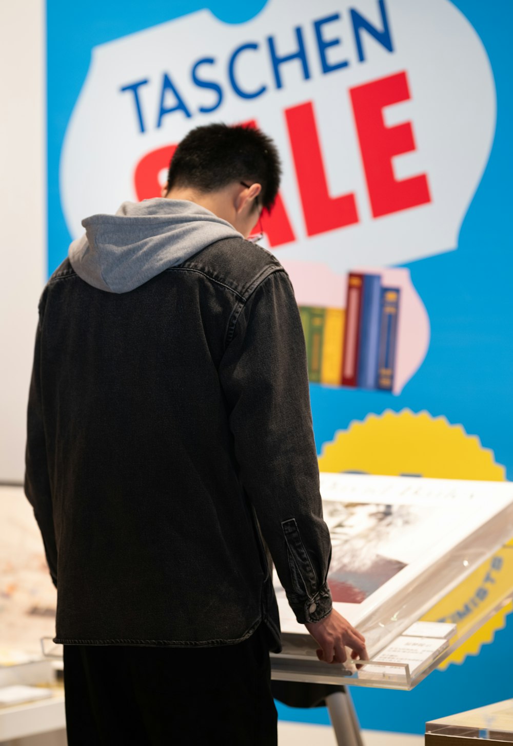 Um homem parado em frente a uma placa que diz Taschen Sale