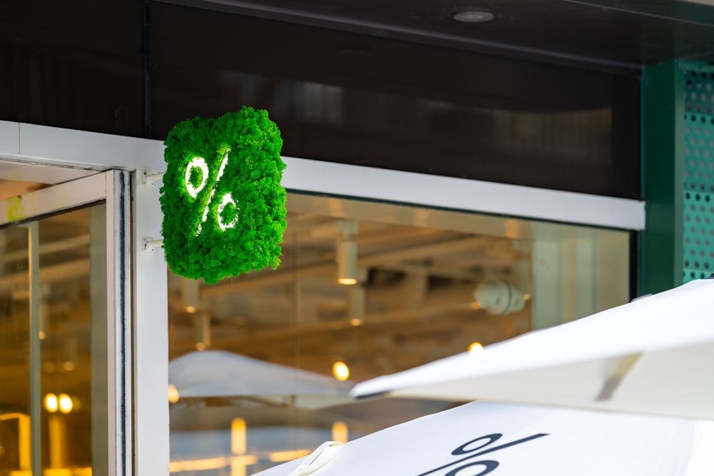 a white umbrella with a green sale sign hanging from it's side