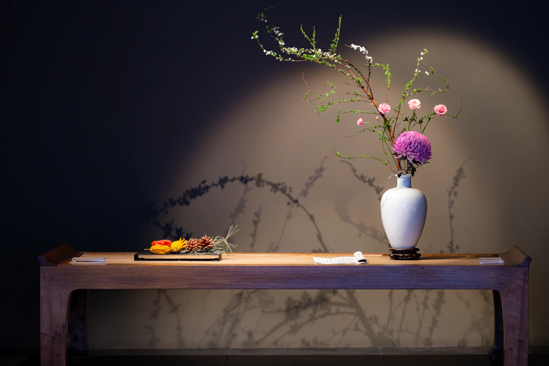 a table with a vase of flowers and a plate of food on it