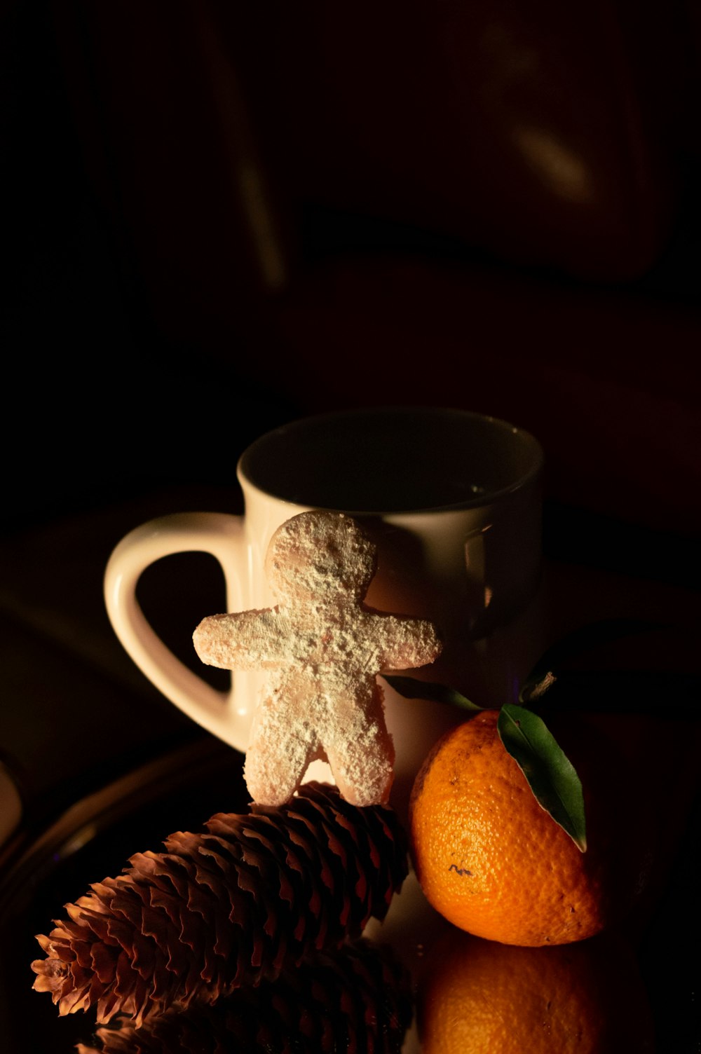 a cup of coffee, a pine cone, and a cookie on a plate