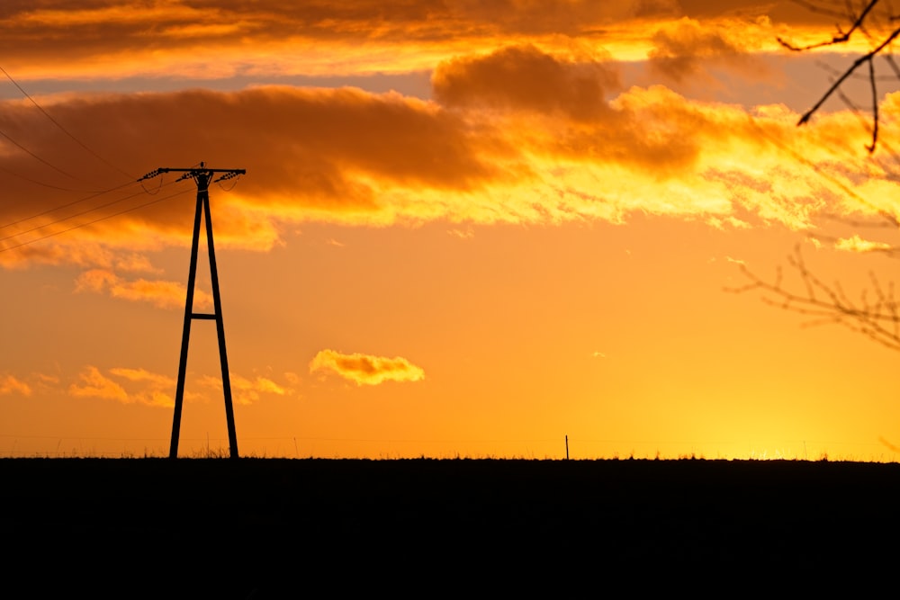 the sun is setting over a field with power lines