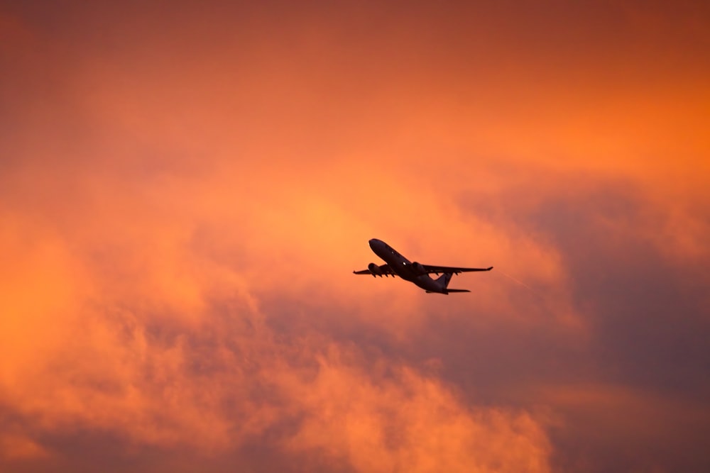 an airplane is flying in the sky at sunset