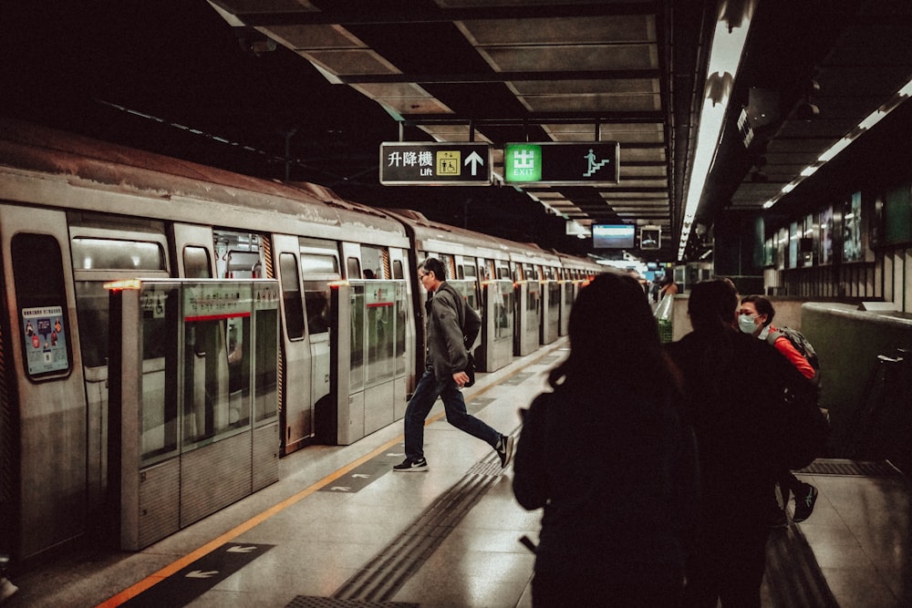 a group of people standing next to a train at a train station