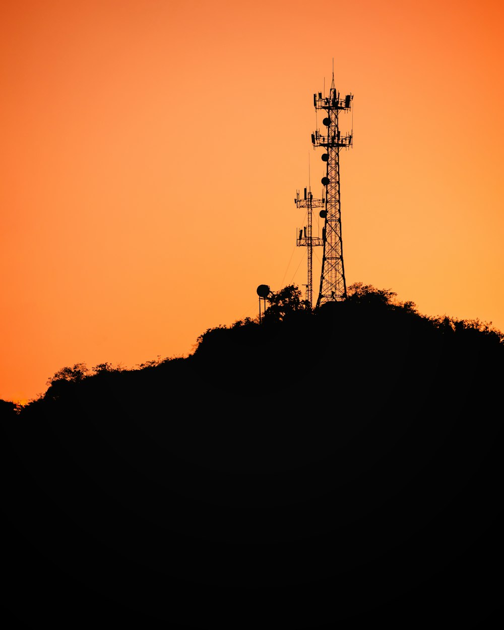 a tower on a hill with a sunset in the background