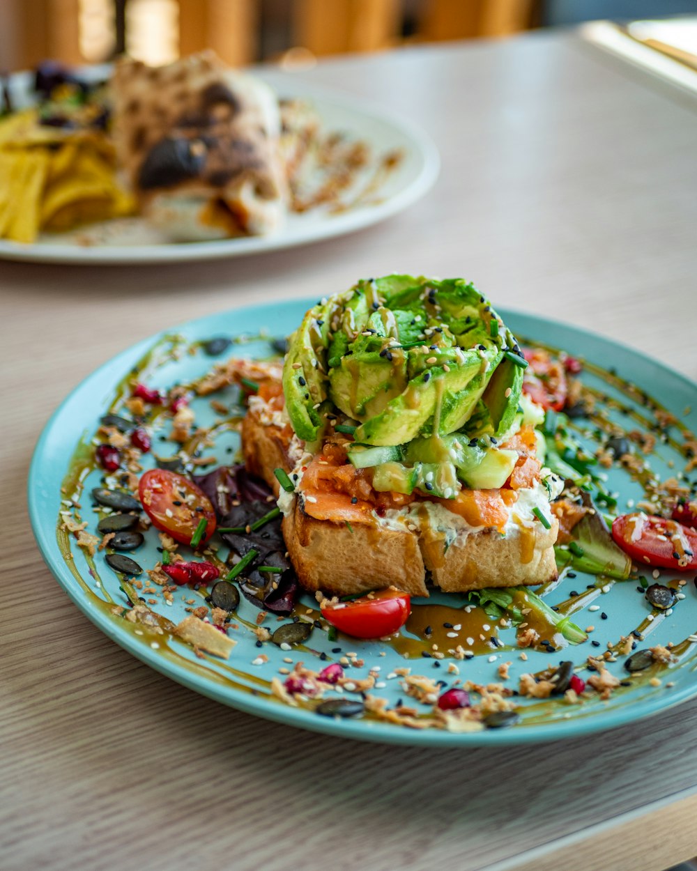 a blue plate topped with a piece of bread covered in veggies