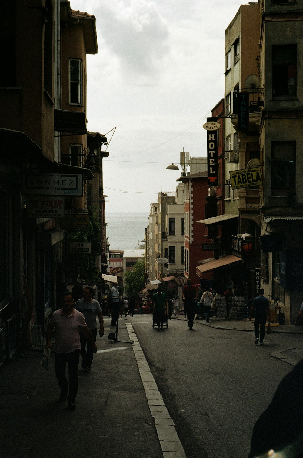 a group of people walking down a street next to tall buildings