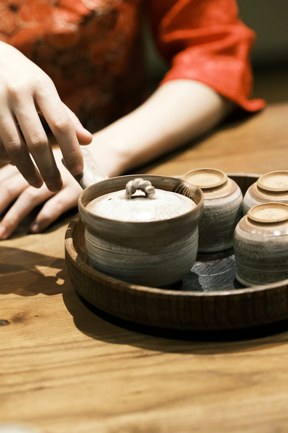 a person sitting at a table with a plate of pottery