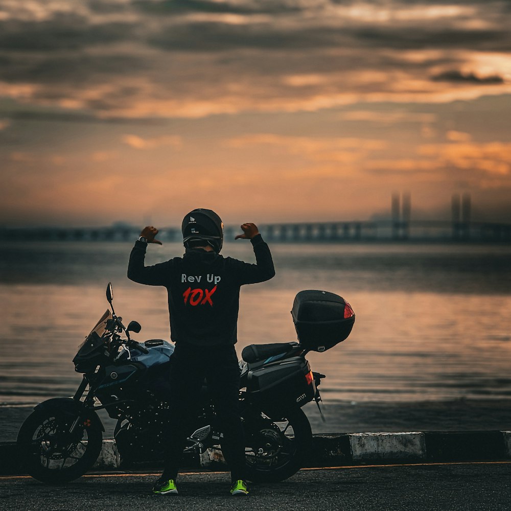 a man sitting on a motorcycle next to a body of water