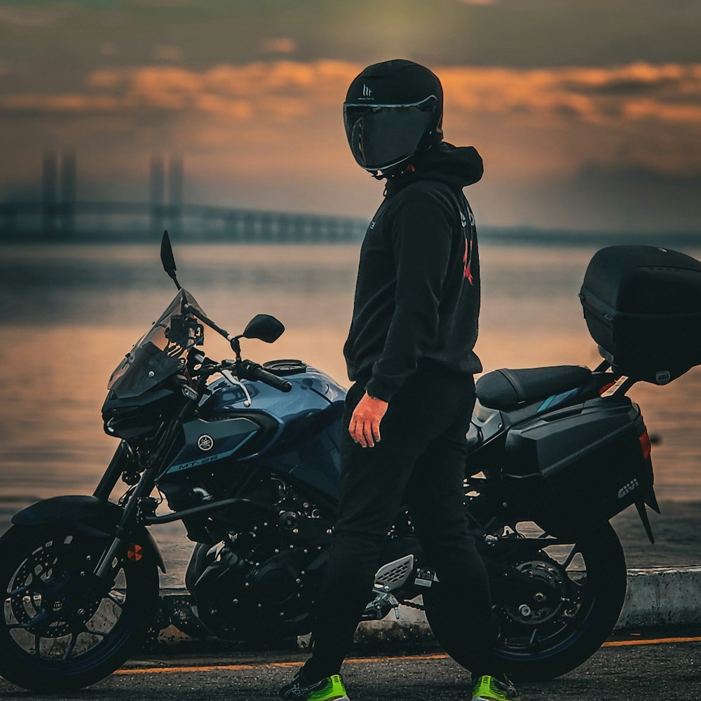 a man standing next to a motorcycle near a body of water