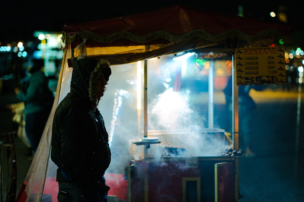 a man standing in front of a stand with smoke coming out of it