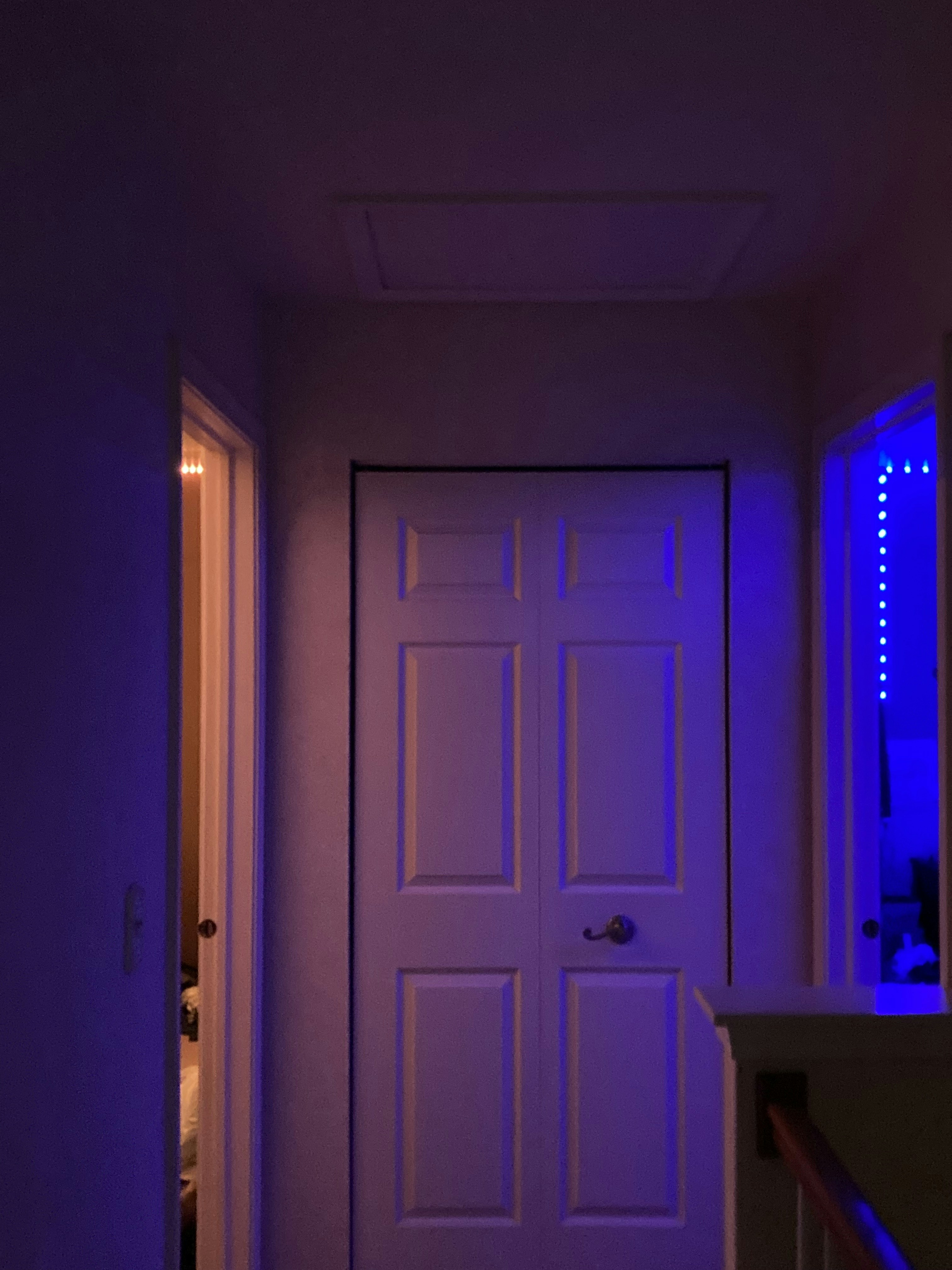 a hallway with a white door and a purple light