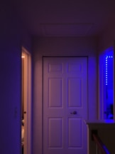 a hallway with a white door and a purple light